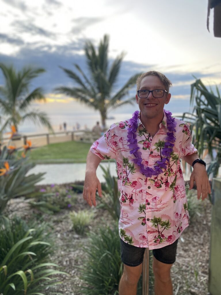 young man with a pink shirt using NDIS short term accommodation with shine to visit the beach